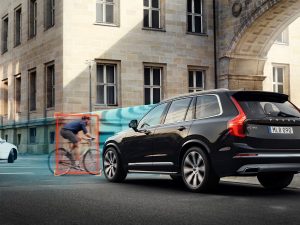 Nuevo sistema de seguridad Volvo, con vista trasera de SUV color negro deteniéndose ante ciclista detectado por auto