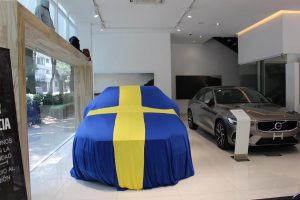 Sedán de lujo cubierto con bandera de Suecia en Agencia de Volvo, vista frontal, previo a revelar el modelo